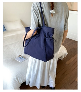Detail view of the deep blue tote bag side drawstring pocket for functional storage
