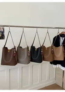 Détail de cinq grands sacs cabas en cuir grainé avec boucles dorées et breloque ours