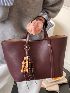 Large burgundy tote bag with leather texture and wooden beaded tassel accessory