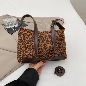Detail of leopard print canvas handbag with brown leather stitching and adjustable strap