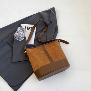 Detail of caramel suede and dark brown leather stitching on a bucket bag