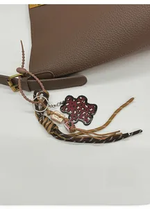 Détail d'un bijou de sac léopard avec corde tressée et anneau sur un sac en cuir brun