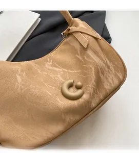 Gros plan du sac porté épaule kaki avec texture cuir craquelé et logo C en métal