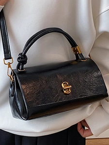 Retro black leather handbag with gold hardware and stylish rope handle on white outfit