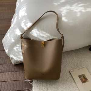 Détail d'un sac seau en cuir marron avec boucle en métal doré et logo de marque gravé