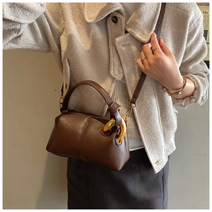 Détail du sac à main marron en cuir litchi avec anneaux dorés et bandoulière amovible