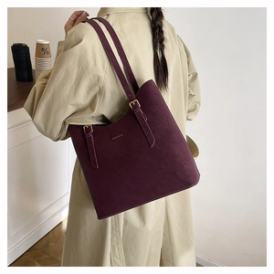 Detail of burgundy suede tote bag with golden hardware and adjustable straps