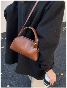 Sac bandoulière en cuir marron grainé porté avec un manteau en tweed noir en automne