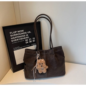Detailed view of coffee brown tote bag with white stitching and plush dog charm