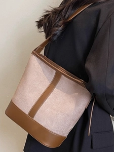 Retro canvas bucket bag with brown leather trim shown as a minimalist shoulder crossbody style
