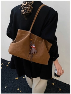 Detail of suede tote bag with large capacity featuring a cute bear doll pendant