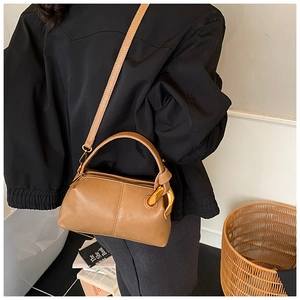 Détail d'un sac à main marron avec grain litchi et chaîne dorée en scène de style de vie