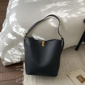 Détail du sac seau en cuir grainé noir avec fermoir rotatif doré et texture raffinée