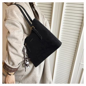 Detail view of the black minimalist suede tote bag featuring a cute cartoon dog charm