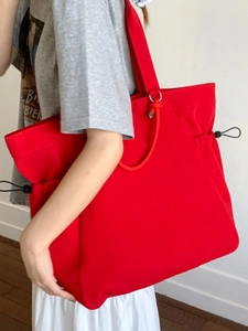 Minimalist bright red canvas tote bag with black side drawstrings and silver rings