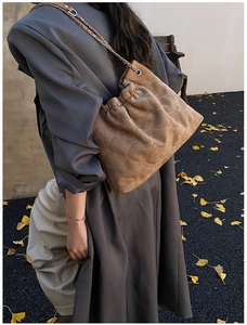 Brown suede quilted bucket bag with chain strap shown in an autumn street setting