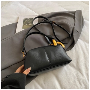 Détail du sac à bandoulière en cuir grainé noir avec une chaîne dorée décorative
