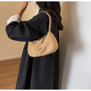 Détail d'un sac hobo beige en cuir souple avec un fermoir en métal doré en forme de C
