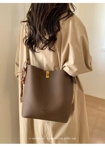Détail du sac seau en cuir grainé marron foncé avec fermoir doré et pampille décorative