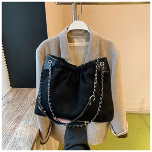 Close-up of black quilted bucket bag with silver chain straps and drawstring detail