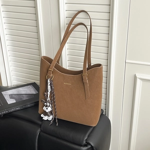 Detail of brown matte tote bag with adjustable gold buckles and Schnauzer dog charm