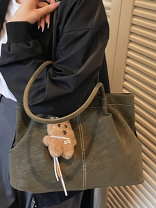 Olive green canvas tote bag with contrast stitching and brown bear charm on shoulder