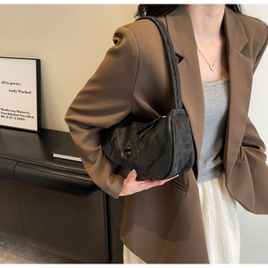 Gros plan sur le sac plissé noir avec grande boucle décorative et finition texturée