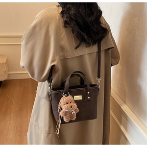 Deep brown suede handbag with golden metal logo and a cute plush puppy pendant detail