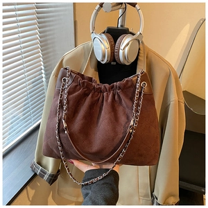 Detail of coffee brown quilted bucket bag featuring drawstring closure and metal chain strap