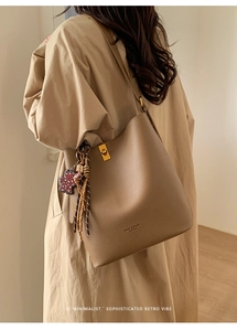 Détail d'un sac seau en cuir grainé avec fermoir doré et pendentif décoratif