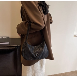 Détail du sac hobo noir avec texture plissée unique et logo décoratif en forme de C