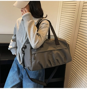 Detail of a large dark grey waterproof fitness bag with wide handles and shoulder strap