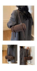 Detailed view of dark brown cylindrical bag with matte texture and silver buckle strap