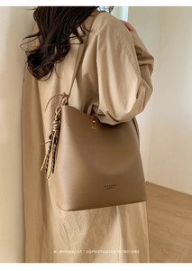 Détail d'un sac seau en cuir marron avec fermoir tournant et sangle tissée latérale