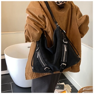 Close-up of black suede hobo bag with silver zipper details and adjustable shoulder strap