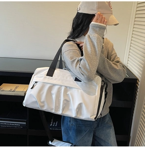 White waterproof sports duffel bag with black straps worn by a person in a minimalist interior