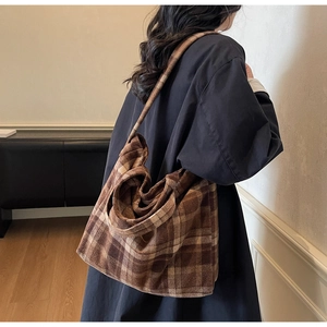 Détail d'un grand sac fourre-tout à carreaux marron montrant sa capacité et sa texture