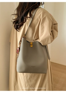 Détail du sac seau en cuir gris avec fermoir doré et pendentif décoratif élégant