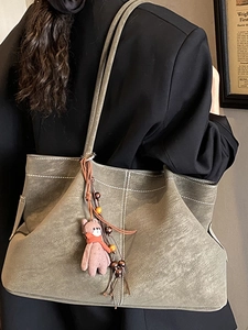 Vintage moss green suede tote bag with white stitching and bear charm worn by a model