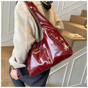 Große weinrote Hobo-Tasche aus Lackleder mit silbernen Nieten getragen am Model