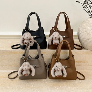 Chic bucket bags in four colors with plush rabbit charms on elegant stone steps