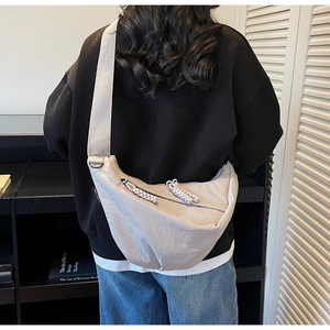 Detail of light beige crescent crossbody bag with adjustable wide strap and zip puller