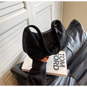 Détail du sac à bandoulière noir en forme de croissant avec fermoir en C mat et texture froissée