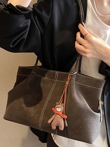 Minimalist brown suede tote bag with contrast stitching and cute bear charm shown on shoulder