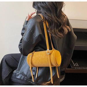 Detail view of bright yellow cylinder bag with fine silver buckle straps and leather texture