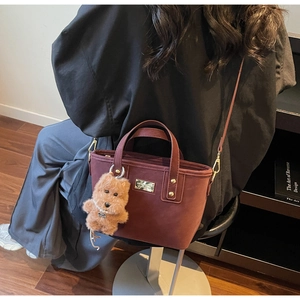 Detail view of burgundy suede tote bag with gold rivets and cute puppy charm