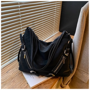 Detail of black tote bag with white contrast stitching and silver zipper pockets