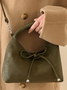 Minimalist moss green square crossbody bag with bow drawstring on winter coat background
