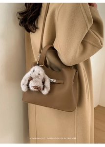 Brown leather bucket bag with silver buckle and plush rabbit charm detail