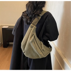 Detail view of olive green nylon crescent bag showing its pleated texture and wide strap